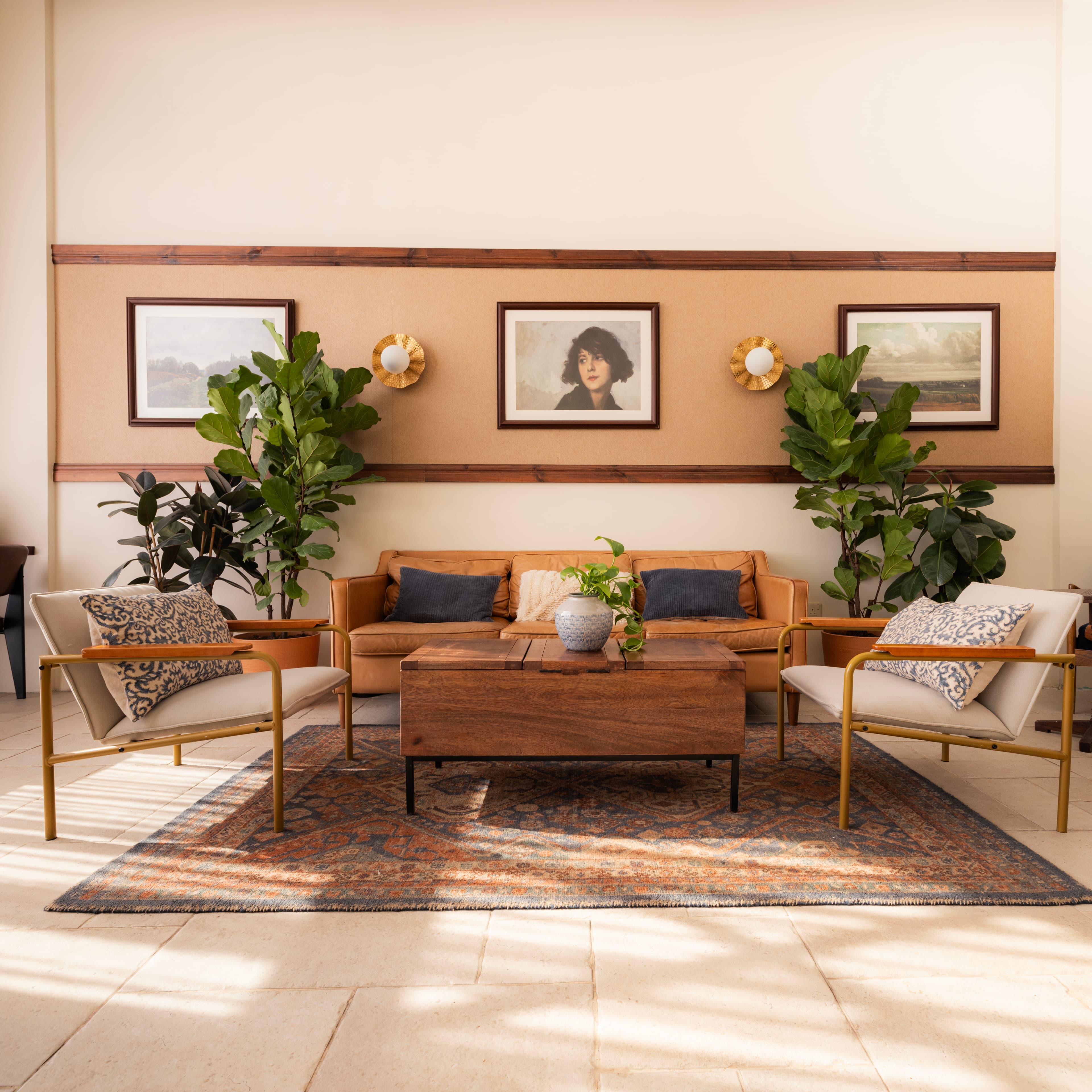 Atmosphere interior — fiddle-leaf plants, vintage couch, framed landscapes